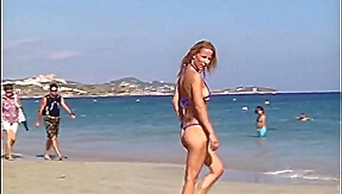 Hot blonde milf posing on public beach in string bikini
